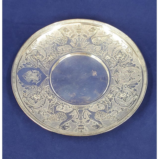 This Tiffany & Co 7" sterling silver saucer / plate has intricate engravings with 2 pairs of griffins or dragons opposite...