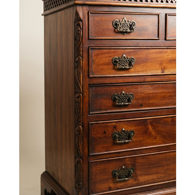 A striking Chippendale-style highboy featuring a beautifully carved scroll pediment with a central finial and intricate...