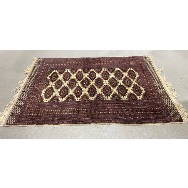 Vintage area rug featuring a striking geometric design inspired by traditional Persian Bokhara patterns. The ivory field...