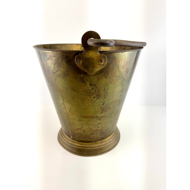 Vintage brass cachepot featuring a classic tapered bucket form, rolled foot, and decorative swing handle. Crafted in solid...