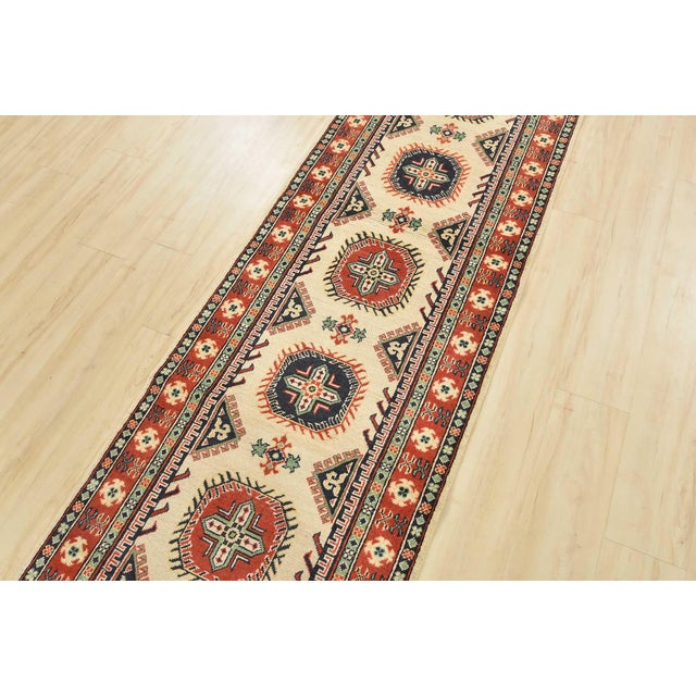 A tribal Caucasian Kazak runner hand-knotted with an all-wool pile on a cotton foundation. This oriental rug features a...