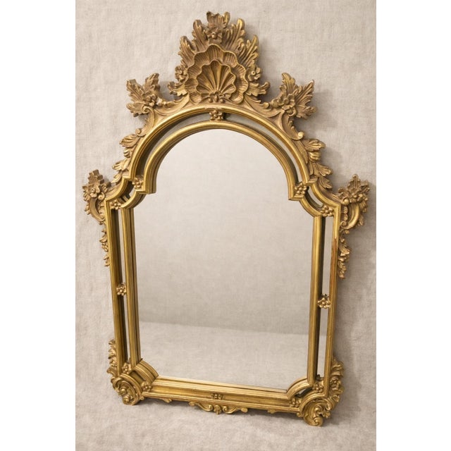 An elegant late 19th-century Rococo Revival mirror, richly finished in warm, hand-applied gilt and crowned with a dramatic...
