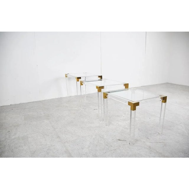 Elegant set of Lucite and Brass Nesting Tables with inset clear glass tops. Nice brass and lucite frames. Charles Hollis...