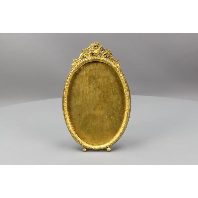 French Louis XVI style bronze oval photo or picture desktop easel frame from circa the 1900s. This adorable picture frame...