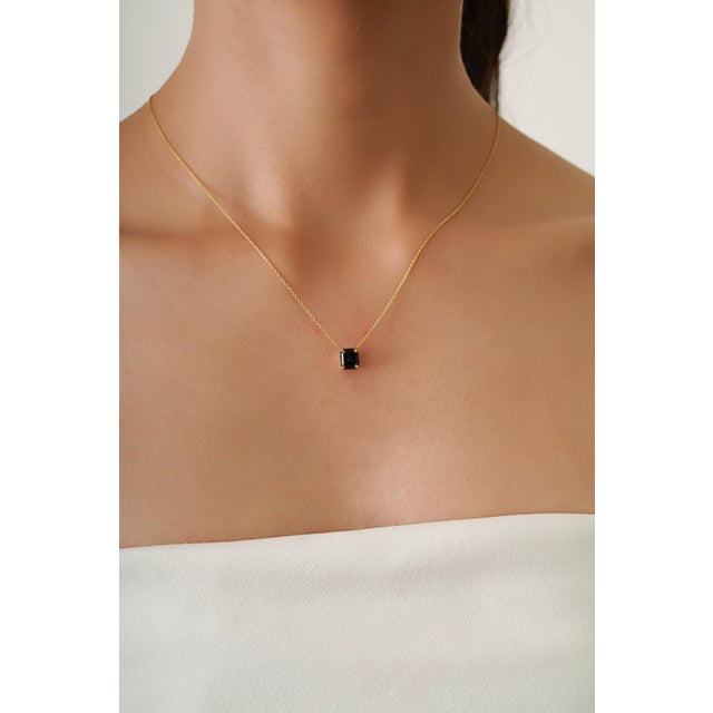 This elegant pendant necklace features a striking 1.82 carat natural black diamond set in 18K yellow gold. and in a...