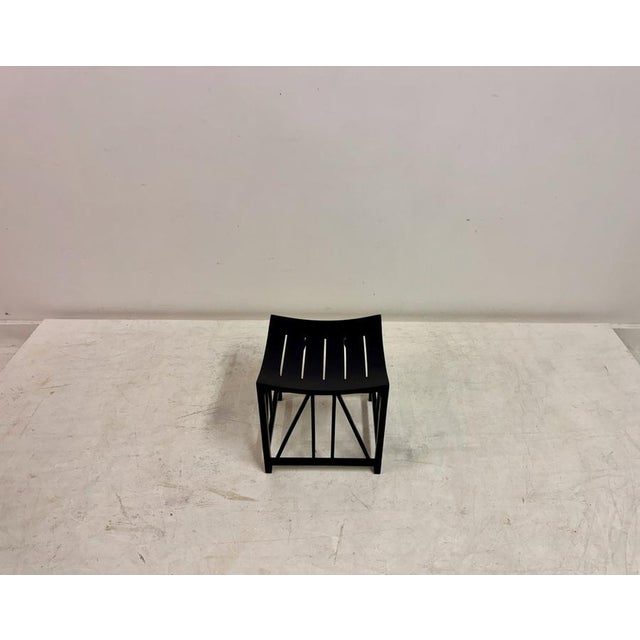 A sculptural black stool in the manner of the “Thebes” form, characterised by its distinctive curved seat and...