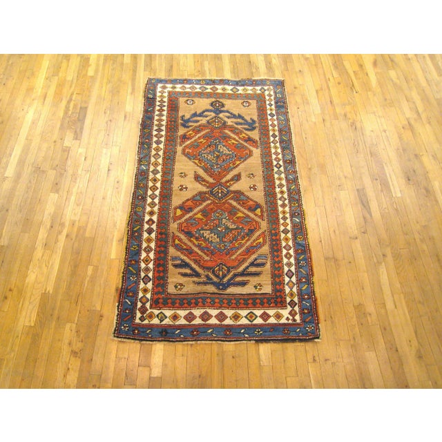 An antique Persian camel hair Serab oriental rug, size 7'4" x 3'6", circa 1900. The rug is characterized by two...