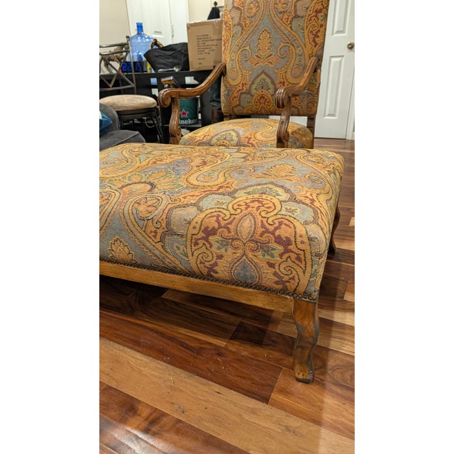 A matching armchair and ottoman from Guy Chaddock & Co.'s Westbourne Collection, upholstered in a rich paisley tapestry of...
