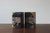 A pair of bookends made of natural, multicolored marble, featuring a compact, geometric design. The cuboid forms are...
