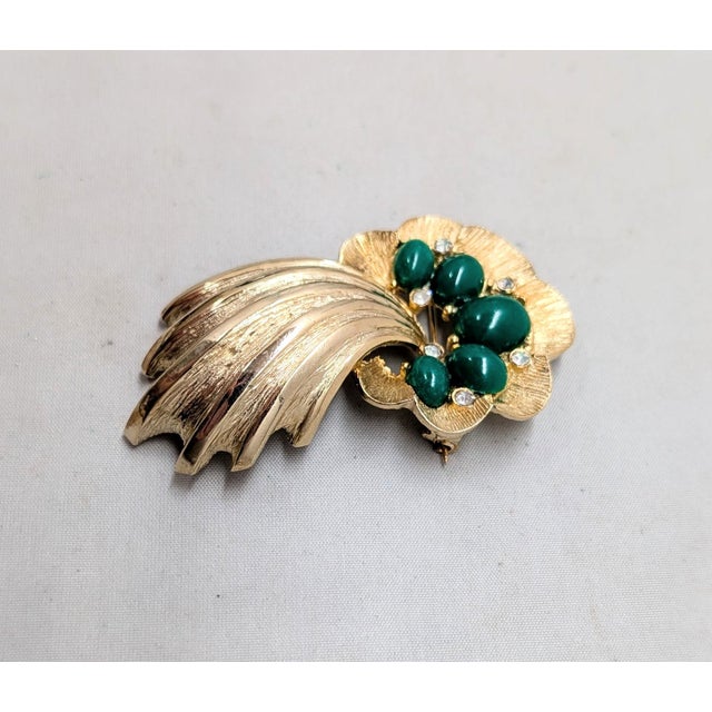 1961 goldtone oval cabochon faux-jade with small round clear rhinestone accents comment brooch with security clasp. Marked...