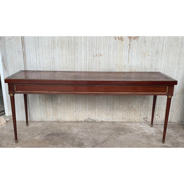 Louis XVI style (19th century) mahogany large console table with a fold-open top, brass trim detail, and tapered fluted...