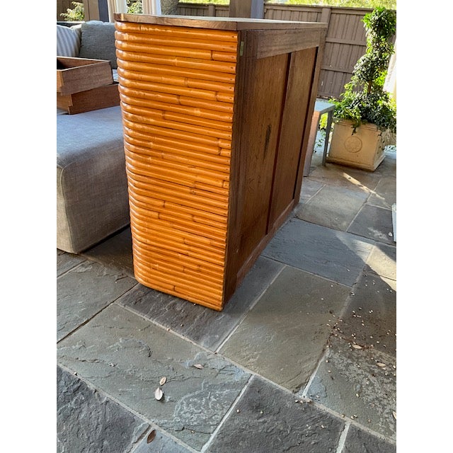 Stacked rattan storage cabinet with a mahogany top and rattan drawer pulls. The cabinet features breakfront storage area...