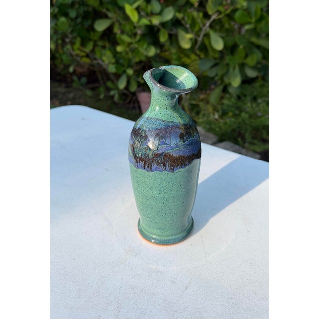 Vintage studio pottery vase featuring a softly rounded form, sculptural flared rim, and richly layered green, blue,...