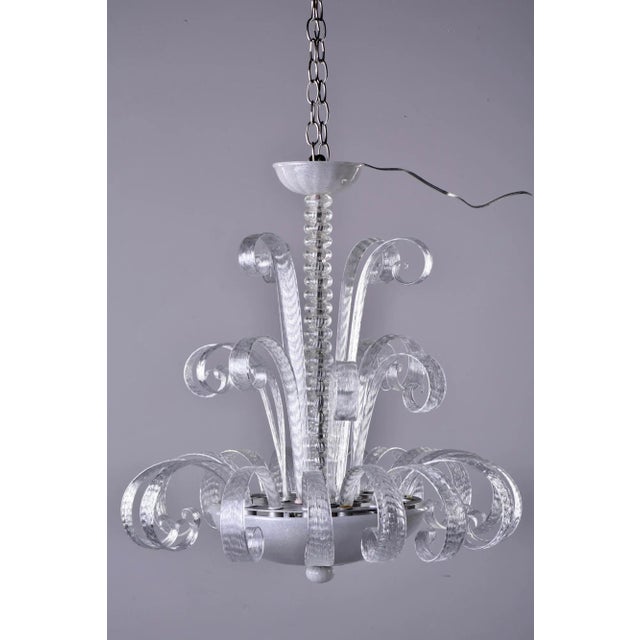 Circa 1940s clear Murano glass chandelier features a center bowl with four sockets and three tiers of curvy glass stems...
