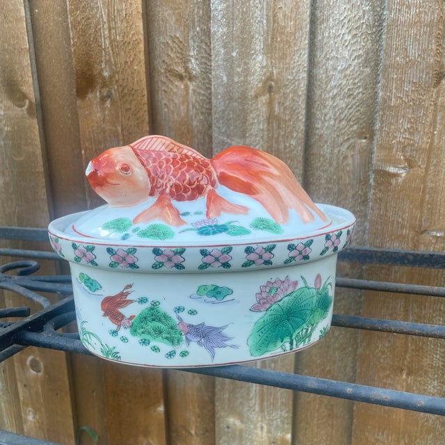 Vintage Chinese Famille Rose porcelain tureen featuring a three-dimensional koi fish handle on the lid. It is hand-painted...