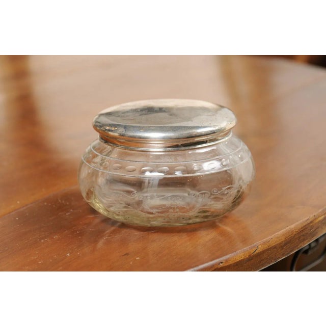 A small English glass vanity jar from the early years of the 20th century, with incised silver lid and etched design....