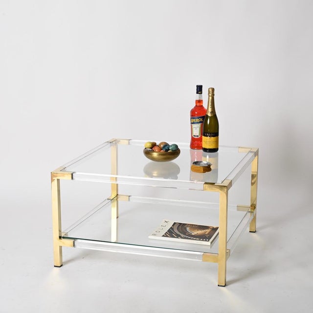 Elegant mid-century large square coffee table crafted from a refined combination of clear acrylic and solid brass. This...