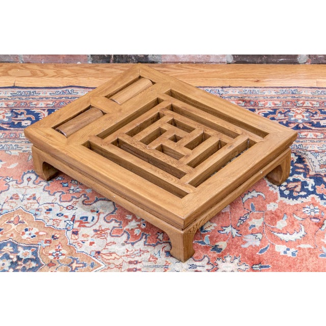 A low Japanese elmwood foot stool with a pierced, latticework top carved in a maze-like geometric fretwork pattern and a...