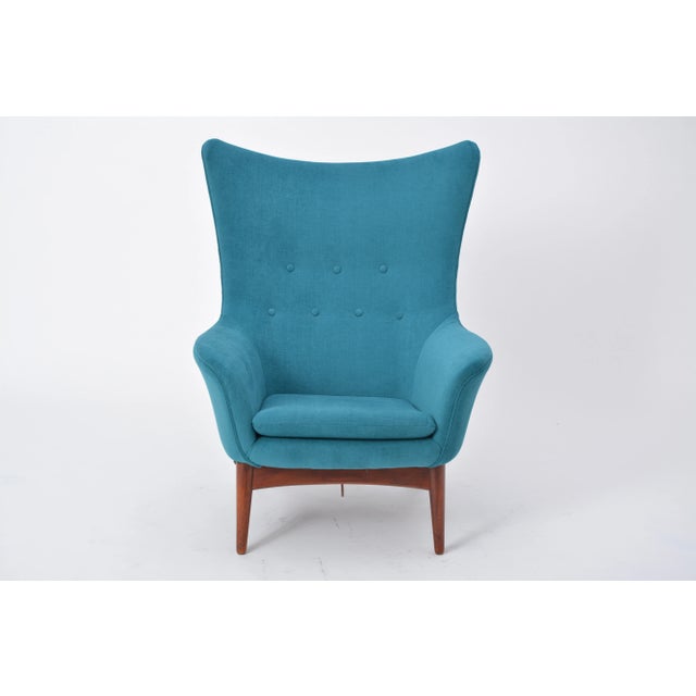 The chair has a rounded design with a subtle wing back and a reclining mechanism, adjusted with a knob on the right-hand...