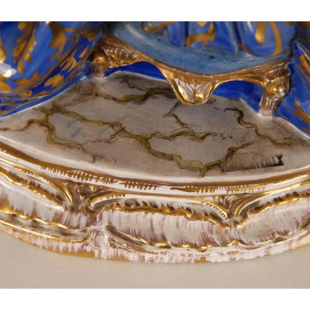 Mid century Art deco porcelain figural sculpture Depicting a lady in a ball gown dress seated on a Rococo style bench Her...