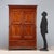 Double-piece wardrobe in walnut-stained poplar. Front with a pair of paneled doors and a drawer underneath, paneled sides,...
