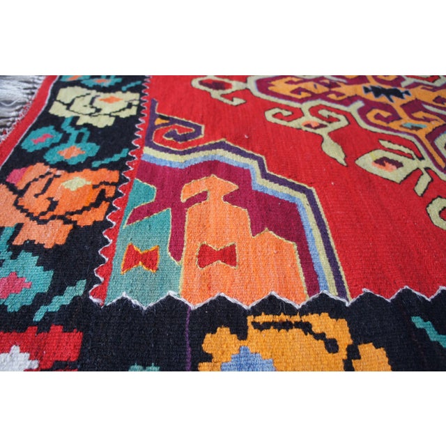 A gorgeous Turkish kilim rug. Red with black boarder and colorful rose design. The perfect compliment in any setting.