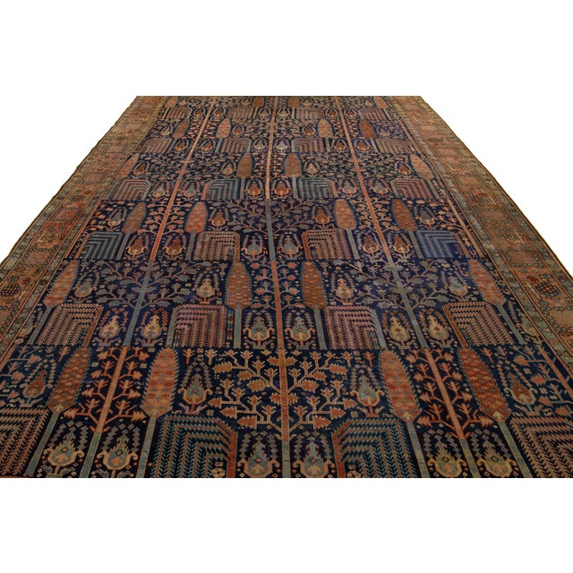 Discover the elegance of a hand-knotted antique Bakshaish rug, featuring vibrant rust accents on a luxurious navy blue...