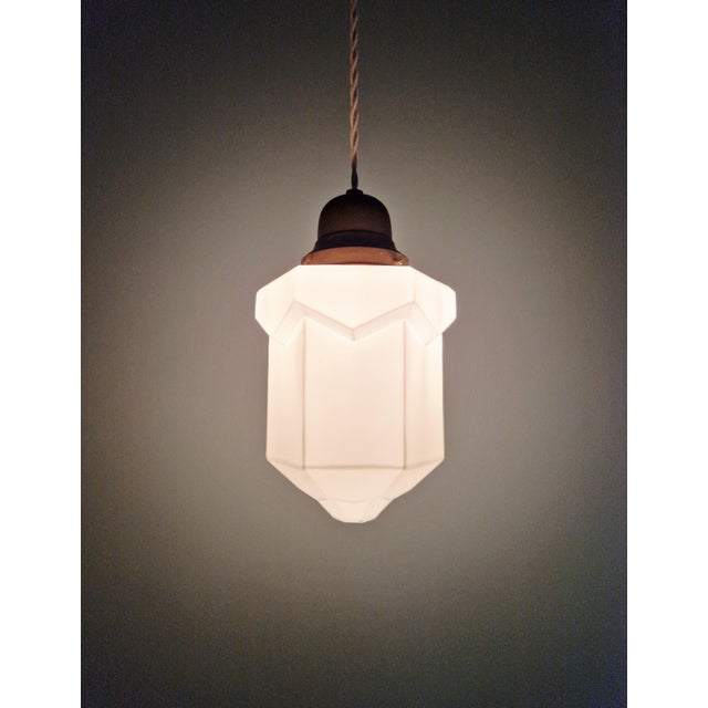White opaline Art Deco Skyscraper pendant light with a copper-plated metal claw and ceiling rose, 1920s-30s. The pendant...