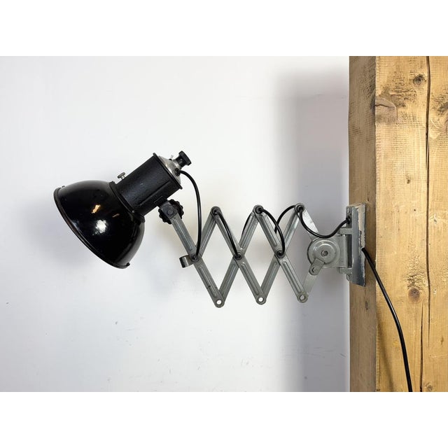 This vintage adjustable Industrial scissor wall lamp was produced in former Czechoslovakia during the 1950s. The lamp has...
