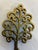 An ornate miniature tree-shaped trivet featuring open scrollwork branches and a warm brass-tone finish. this is a charming...