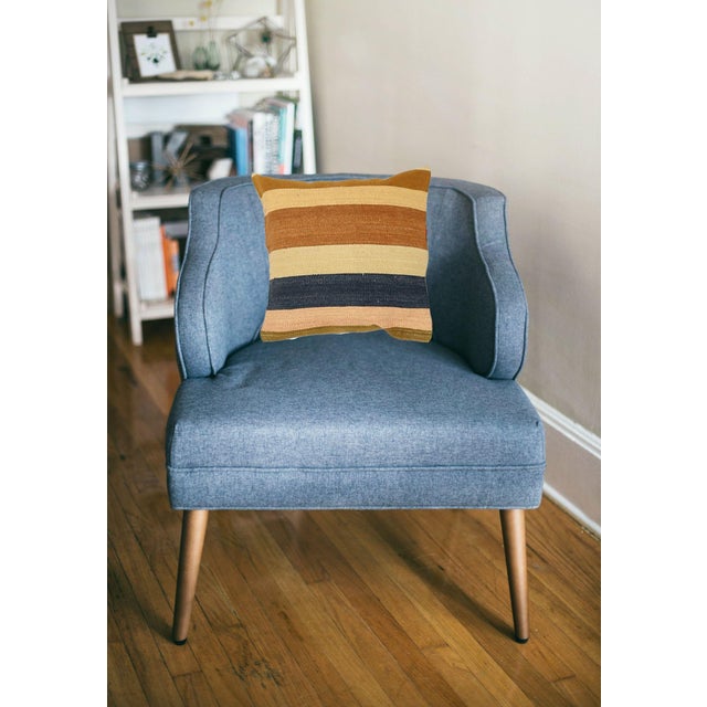 A one-of-a-kind handwoven wool kilim pillow featuring earthy navy, rust, and mustard vertical stripes. Fully reversible —...