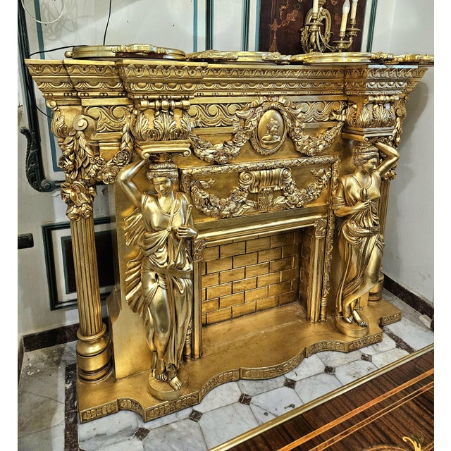 Create a dramatic focal point with this grand French-style fireplace mantel, richly decorated with an elaborate gold leaf...