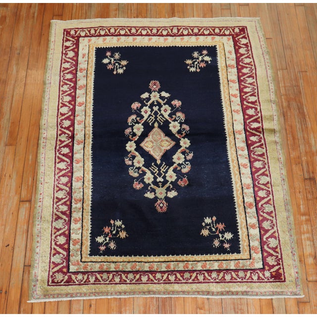 An early 20th century fine Turkish Ghiordes rug featuring an elegant floral motif with a navy ground, accents in peach,...