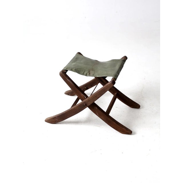 This is a mid 20th century folding camp stool Featuring a dynamic splay leg design, the wood frame stool has a patent...