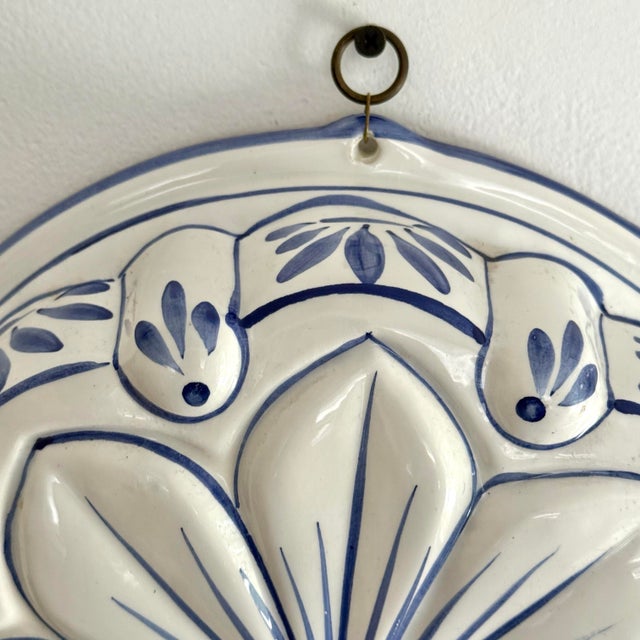 This ceramic mold is shaped as a large open flower in relief, glazed white and detailed in cobalt blue. Hangs on the wall...