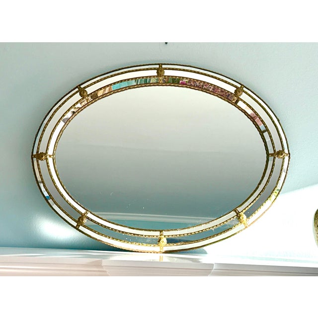 Venetian style Regency modern oval wall mirror with gilt metal accents, Spain, 1960s perfect over a console, in an...