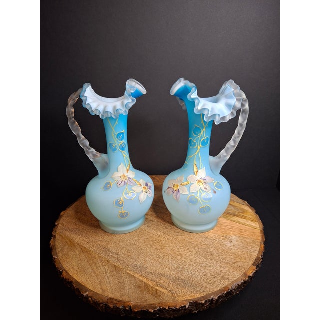 An exceptional, matched pair of late 19th-century Victorian cased satin glass ewers (water pitchers). Each piece is...