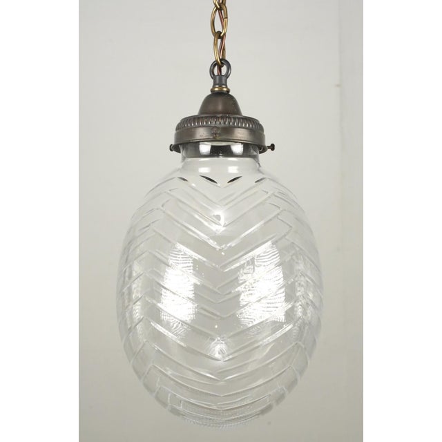Mid Century pressed glass pendant light. The egg shaped shade features geometric patterns, including a chevron design...