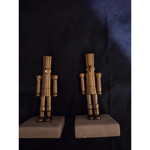 This is a pair of vintage decorative metal nutcracker figurines mounted on heavy rectangular stone or marble bases,...