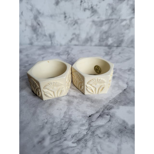 Set of 2 vintage celluloid napkin rings. Both are faceted and have raised floral and leaf design. The original sticker is...