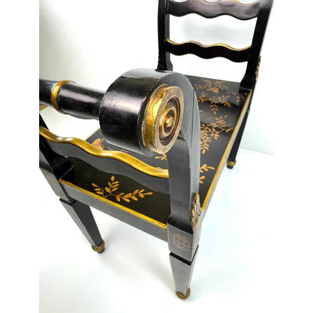 A striking Chinoiserie-style accent bench featuring a black lacquered finish with finely hand-painted gilt decoration...