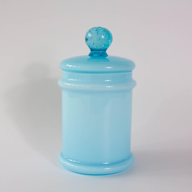 This vintage opaline glass jar with lid, produced in the 1960s in Marinha Grande, Portugal, is a refined example of mid-...
