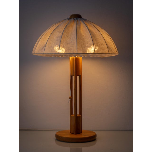 A sculptural Scandinavian pine table lamp from the 1960s-1970s featuring an open architectural frame base and a wide...