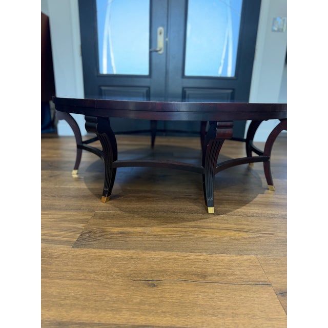 A sophisticated round coffee table crafted by the renowned Hickory Chair Furniture Company, showcasing a richly figured...