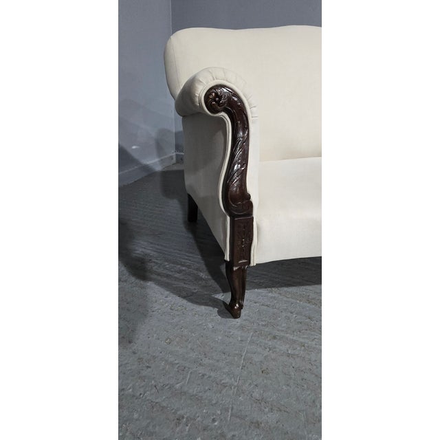 A very good cream plush upholstered two seater couch with a mahogany frame, with curved arms and standing on small...