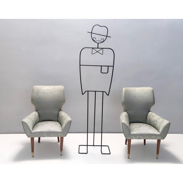 Made in Italy, 1950s. These lounge chairs feature a walnut frame, a silver / light green satin upholstery and cast brass...