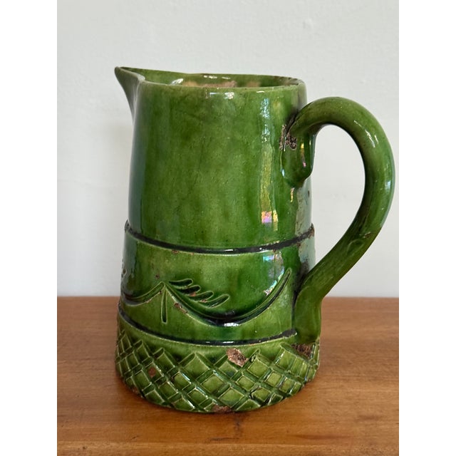 A rustic and antique earthenware pitcher in a striking green glaze. Please see condition details noted. Most items found...