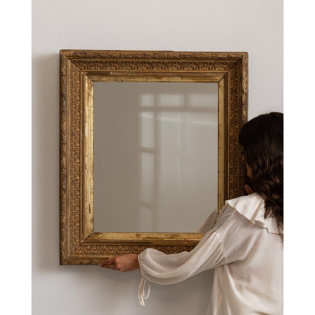 Carved giltwood mirror in Antique Gold. Finished in antique gold, this carved giltwood mirror is distinguished by...