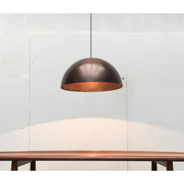Large Mid Century Dome pendant in copper. The shade shows the shape of a hemisphere. The copper surface has a wonderful...