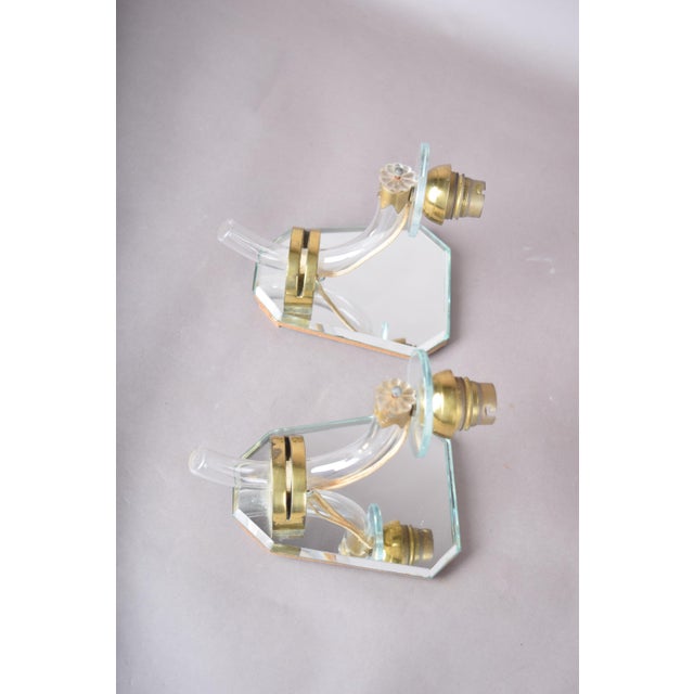 Pair of french art deco wall sconces from the 1940s. Each has a shield-shaped bevelled mirror backplate, a curved clear-...